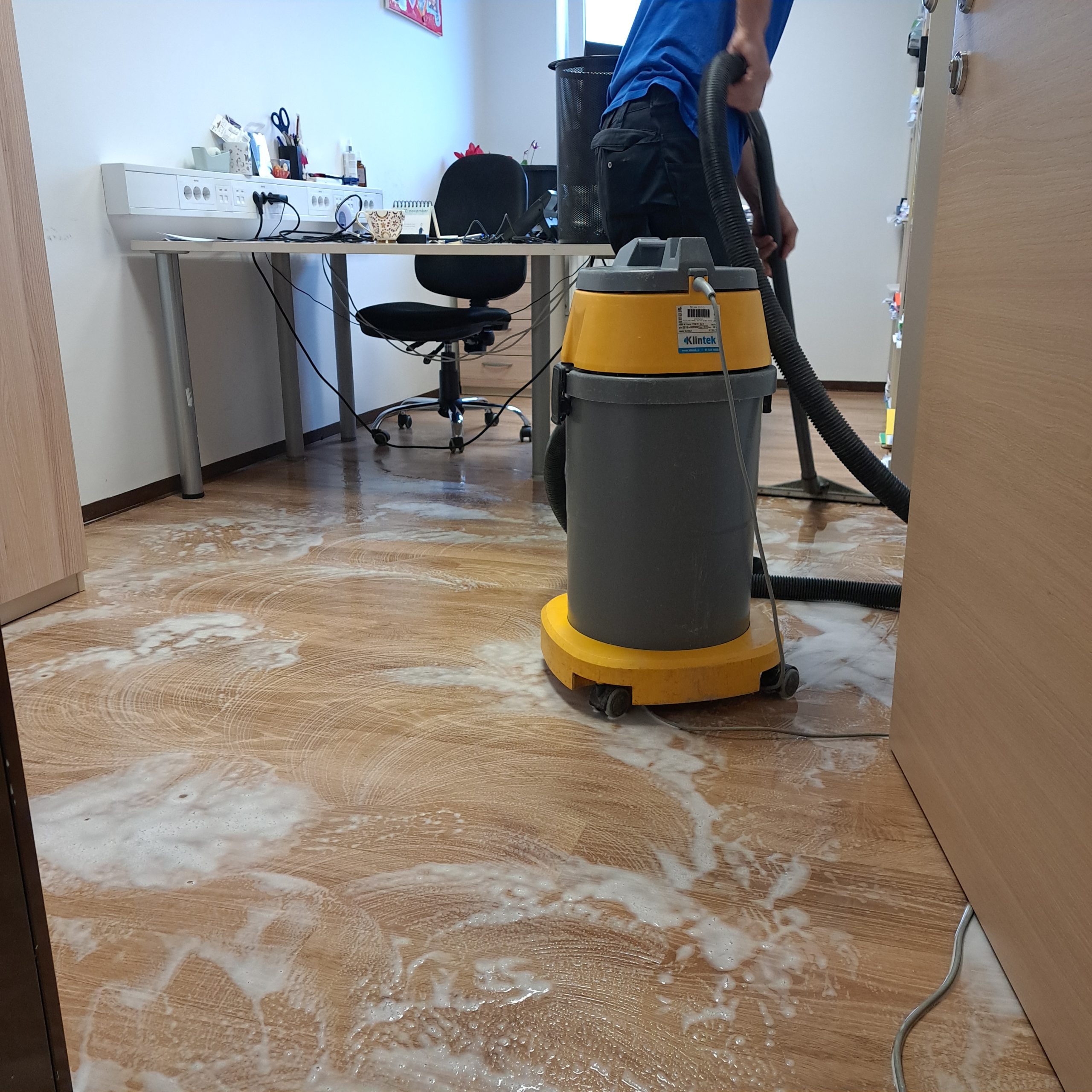Prikaz mokrega čiščenja tal ene od pisarn, ki jo izvaja delavec oddelka Čistilni servis