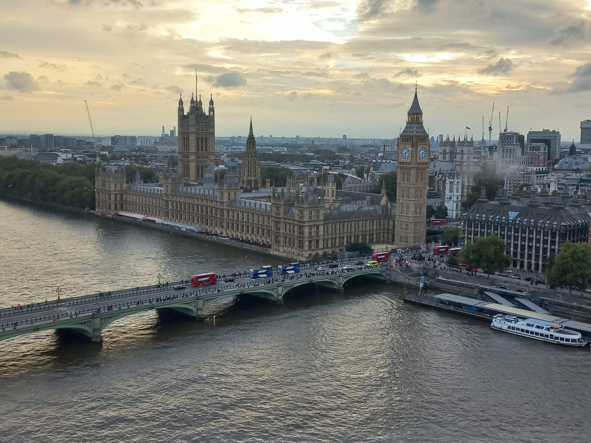 Panoramski pogled na London podnevi z oblačnim nebom, skozi katerega se prebijajo sončni žarki.